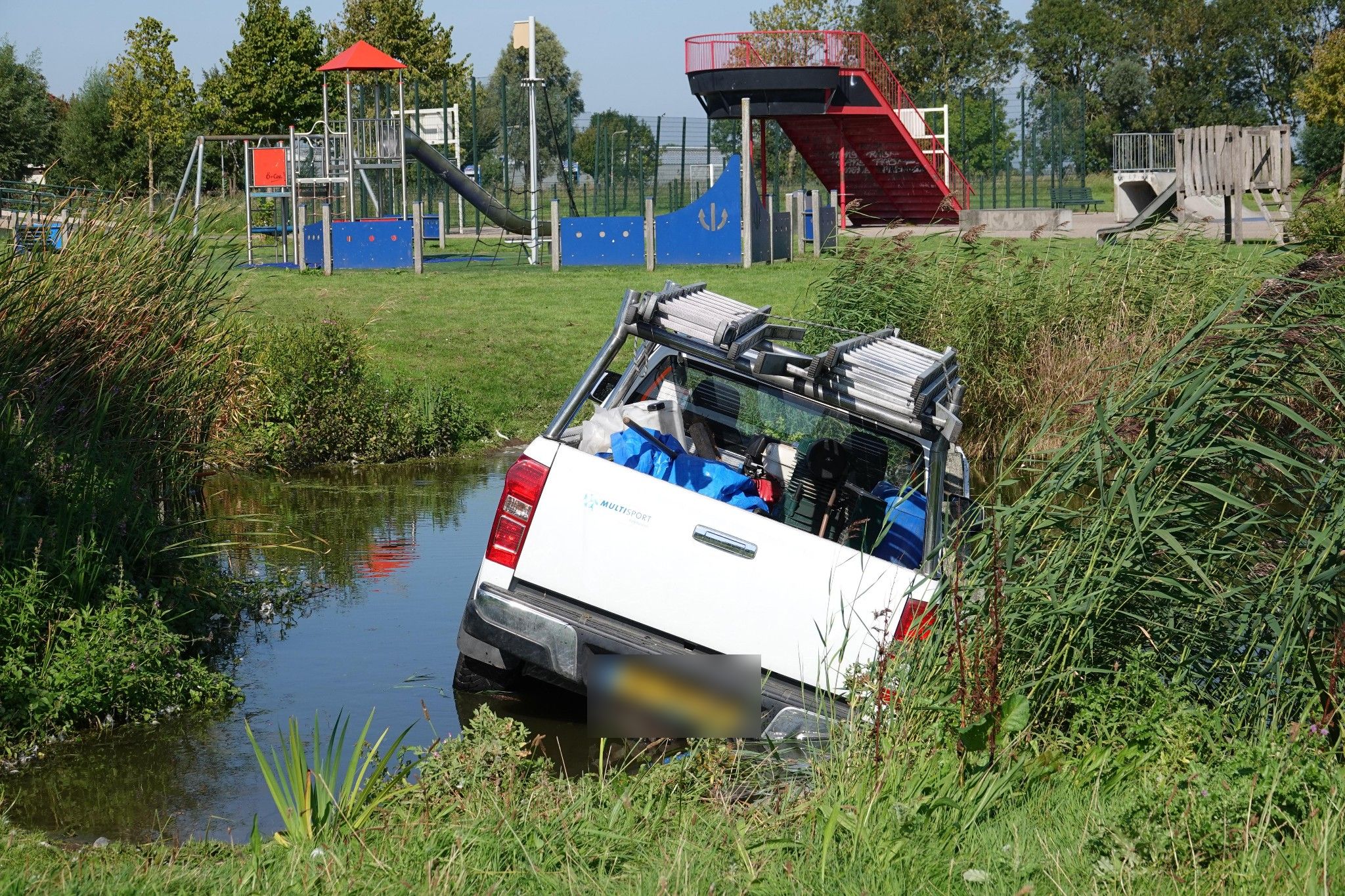 Pick-up van schoonmaakbedrijf vast in water bij Speeleiland Enkhuizen