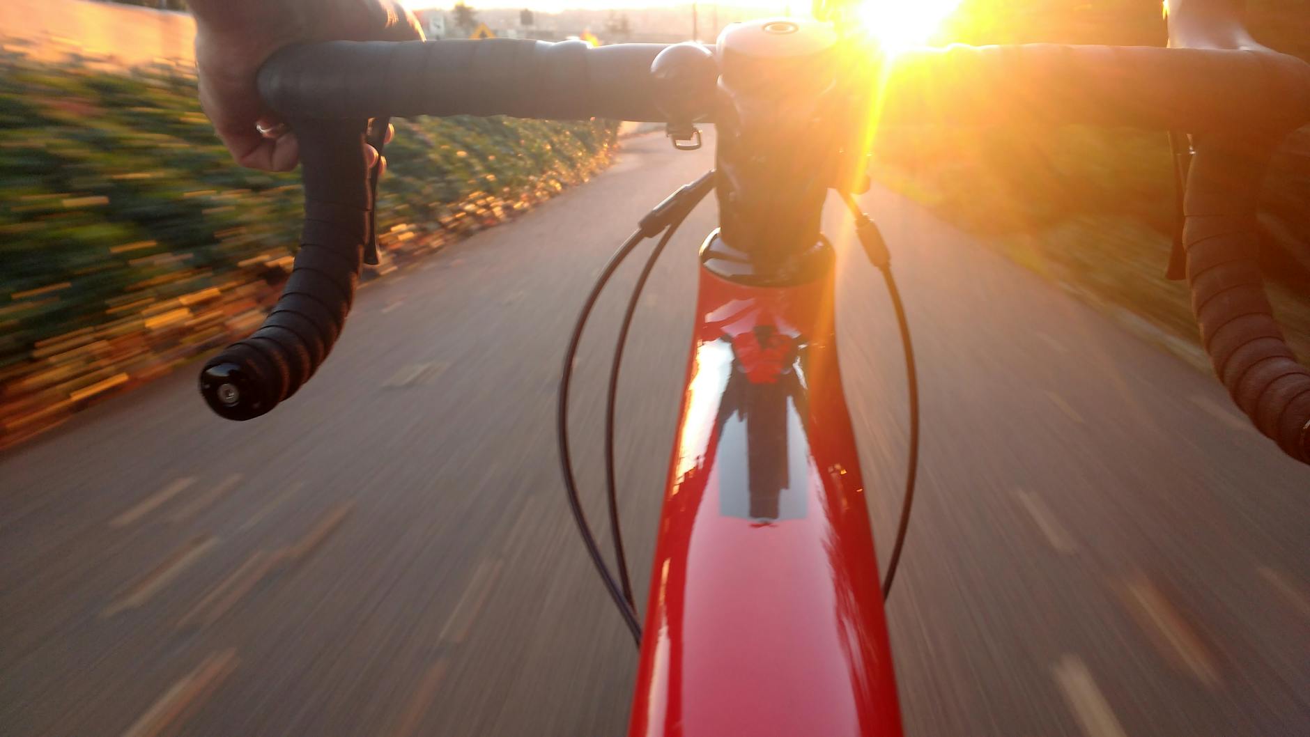 person riding on red road bike during sunset